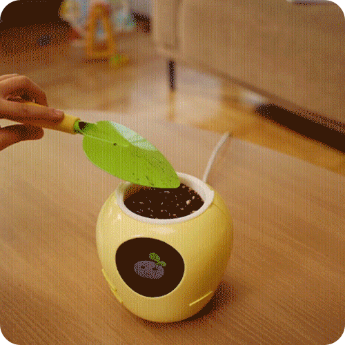PlantBot Smart Plant Pot usage step 1: Action of placing a plant seed directly into the robot pot.